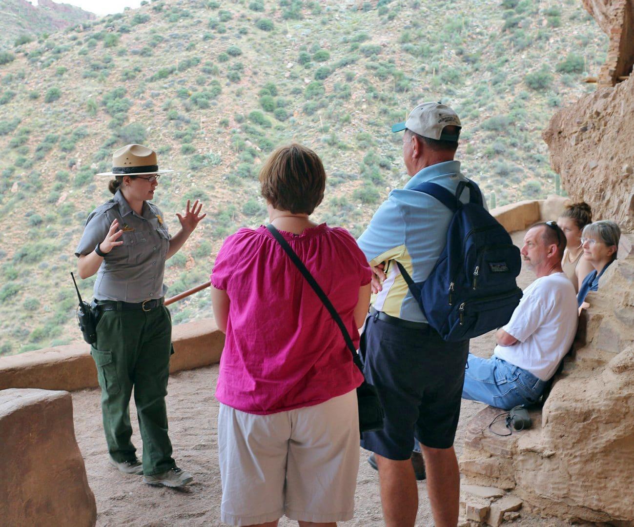 Tour guide speaking to a group on a rocky mountain ledge.