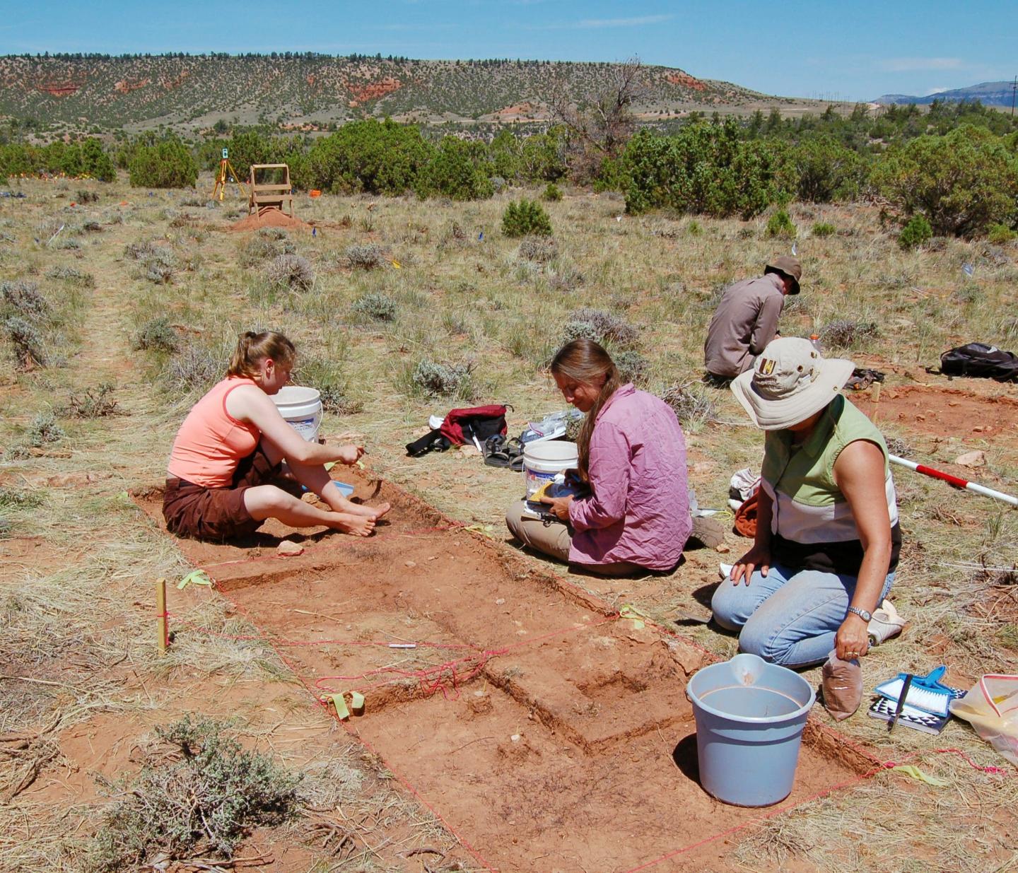 Archaeologists excavating a site in a desert landscape.
