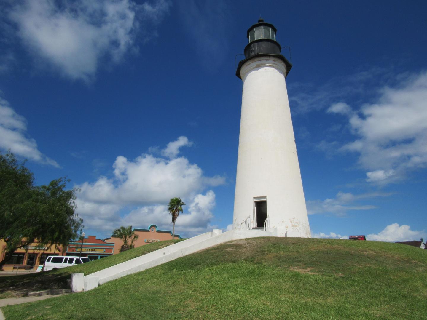 A tall white lighthouse under a blue sky with clouds.