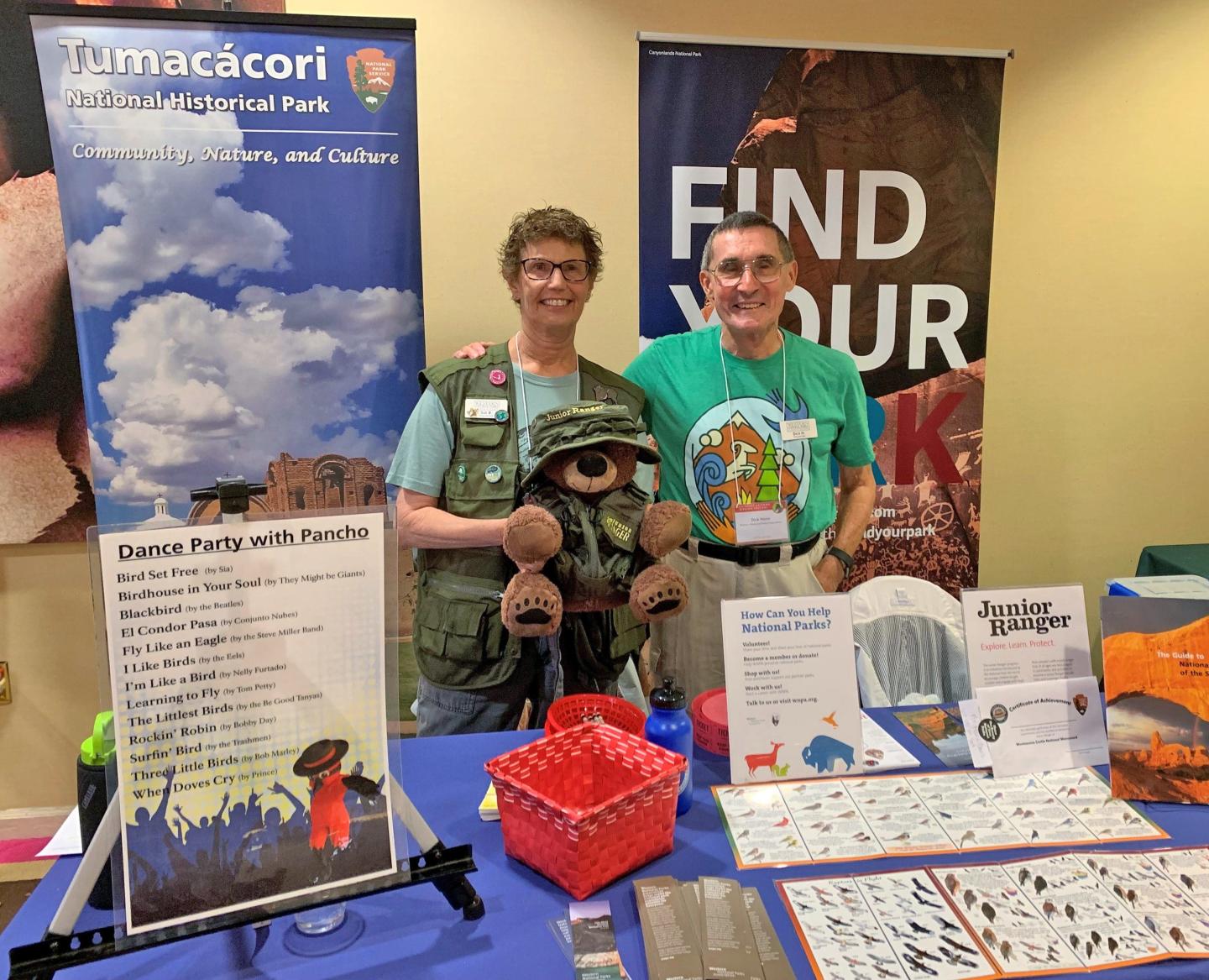 Two people at an informational booth with brochures and banners.