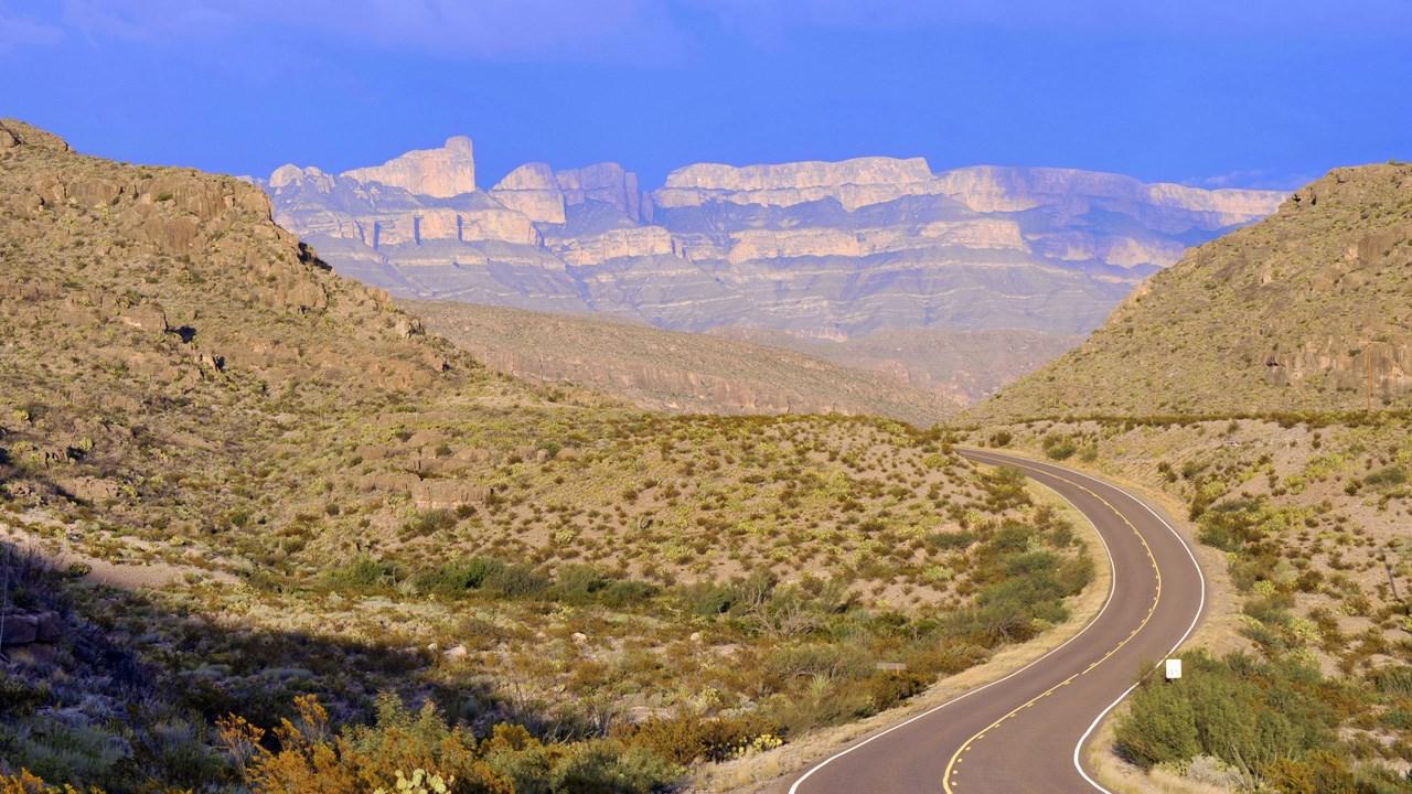 Winding road through desert hills under a bright blue sky.
