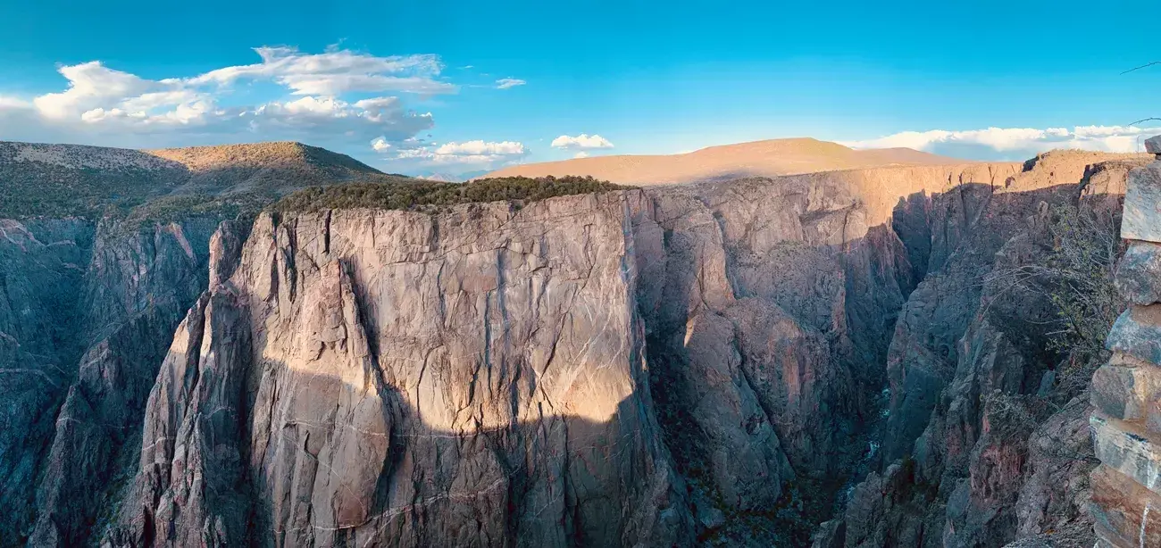 Steep canyon cliffs under a bright blue sky with scattered clouds.