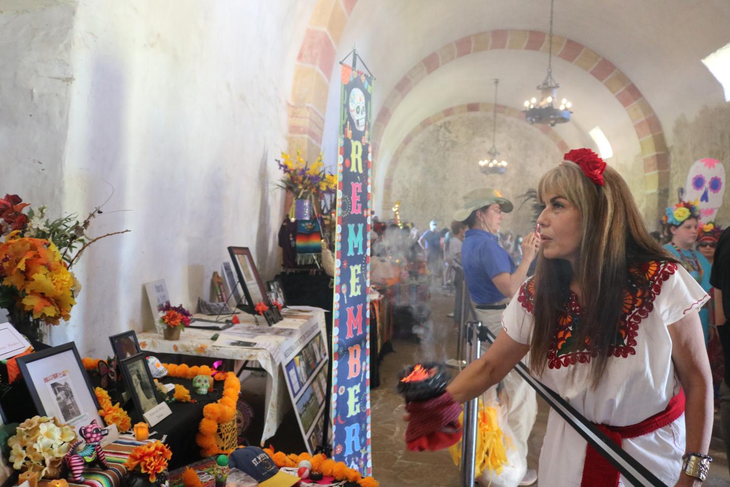 Woman in traditional dress at a vibrant altar during Day of the Dead, Dia de los Muertos, at San Antonio Missions National Historical Park.
