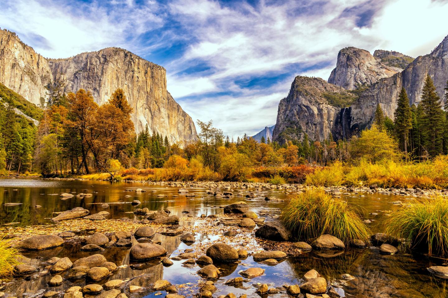Autumn landscape with mountains, river, and colorful trees.