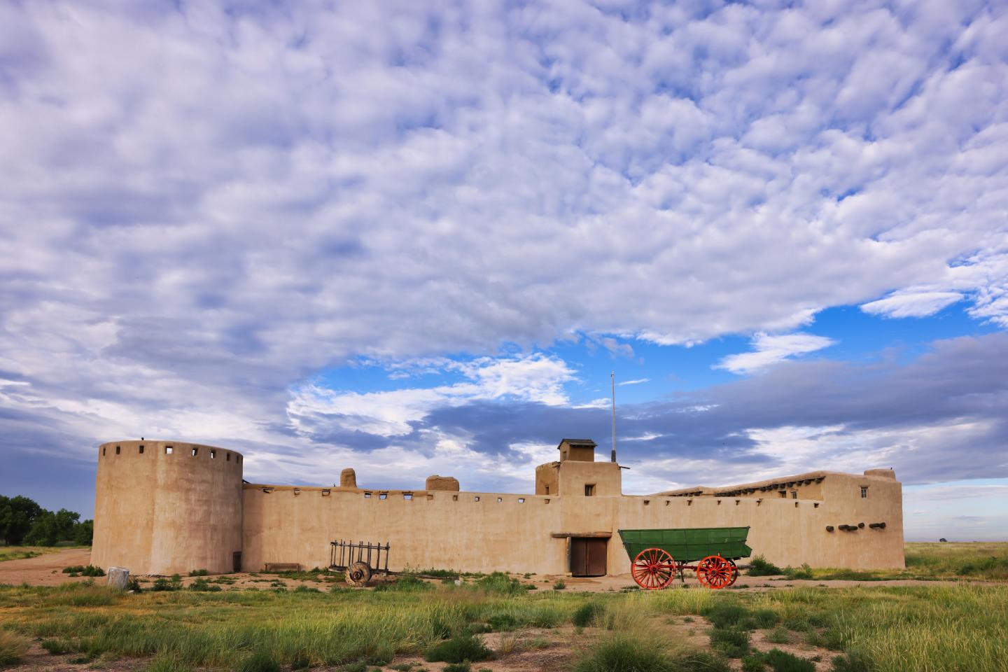 Bent's fort under a cloudy sky with grassy foreground.