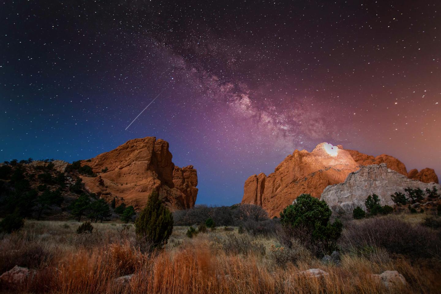 Garden of the Gods over rocky landscape at dusk, Milky Way visible.