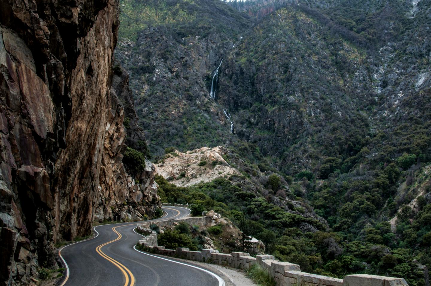 Winding mountain road beside Kings Canyon cliffs.