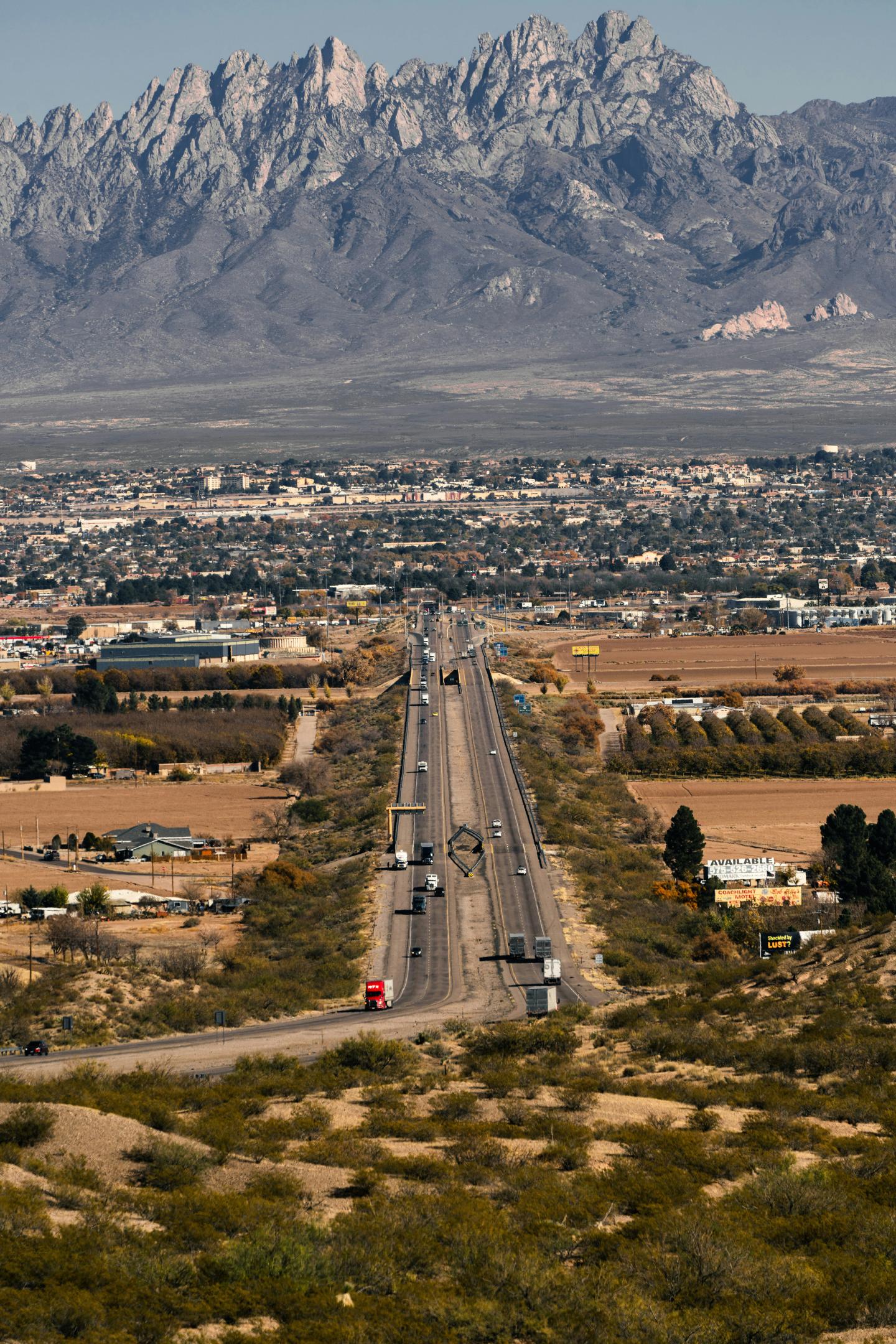 Desert highway stretching towards distant mountains under a clear blue sky.