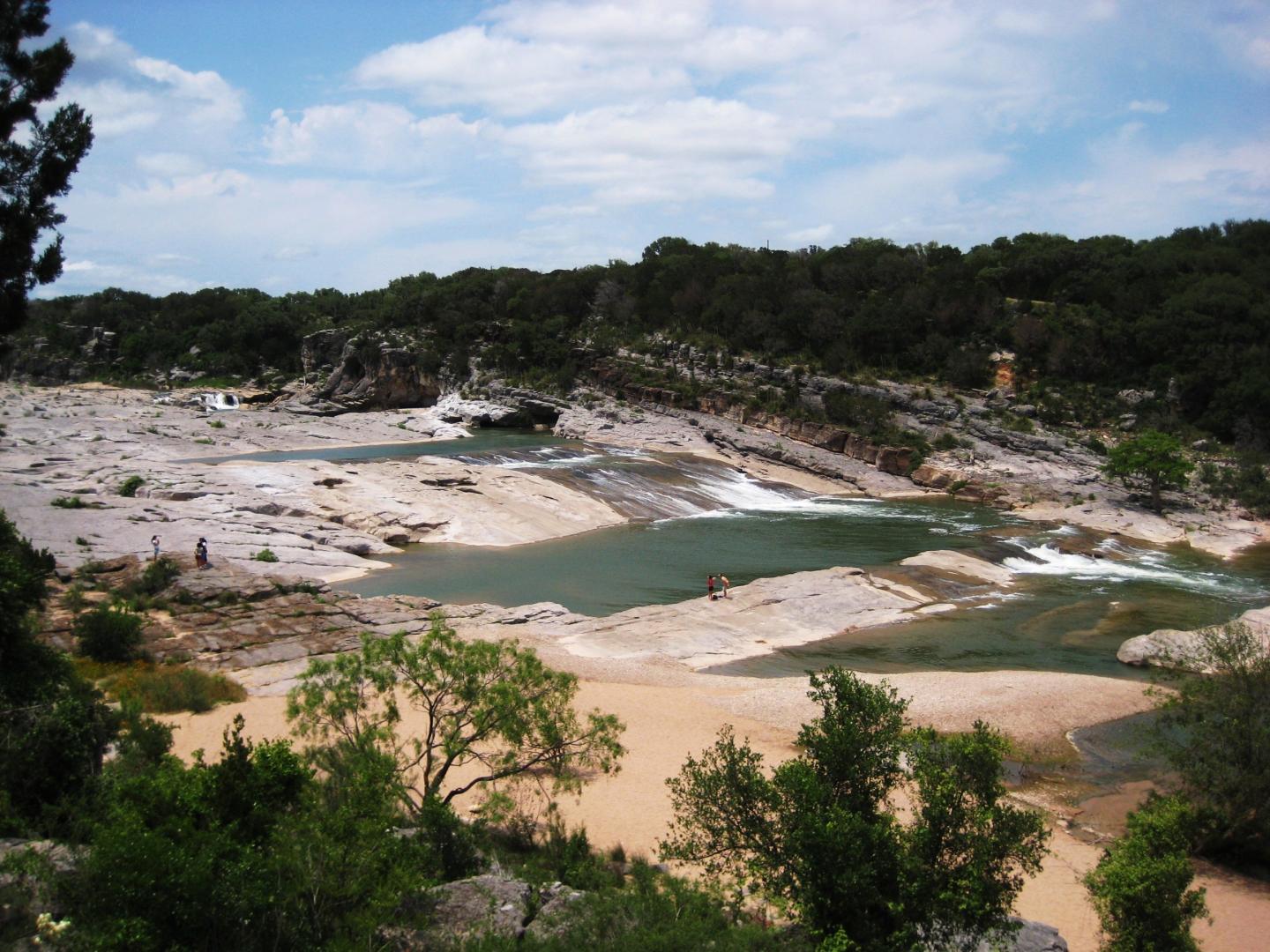Pedernales Falls landscape with trees and blue sky.