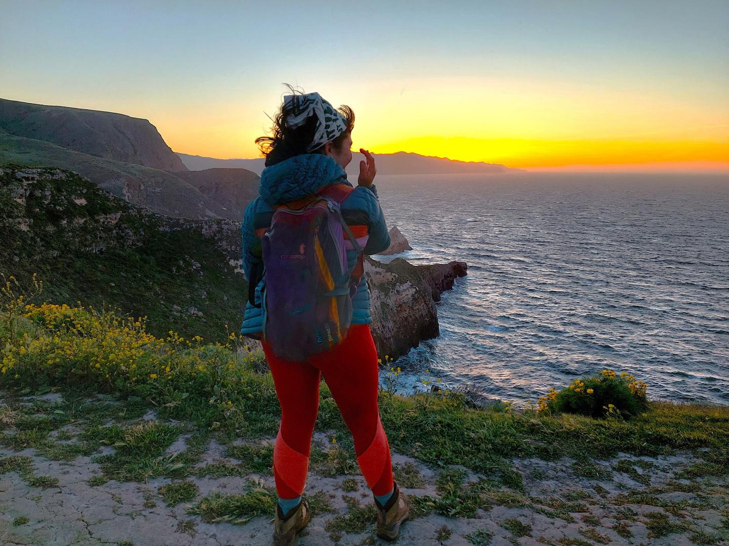 Hiker with backpack watching sunset over ocean cliffs at Channel Islands National Park.