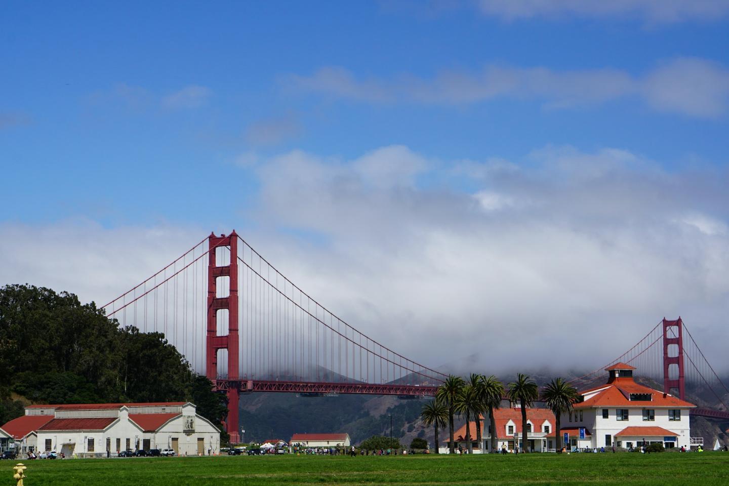 Presidio of San Francisco with cloudy sky and buildings in foreground.