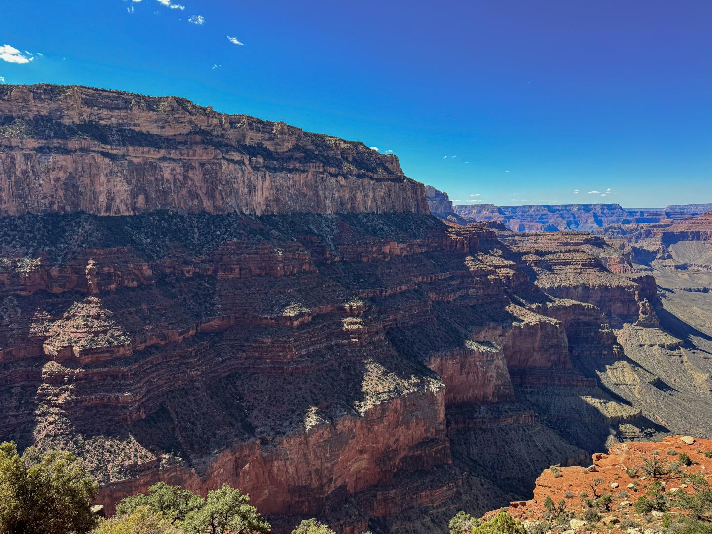 Grand Canyon under clear blue sky, layered rock formations visible.