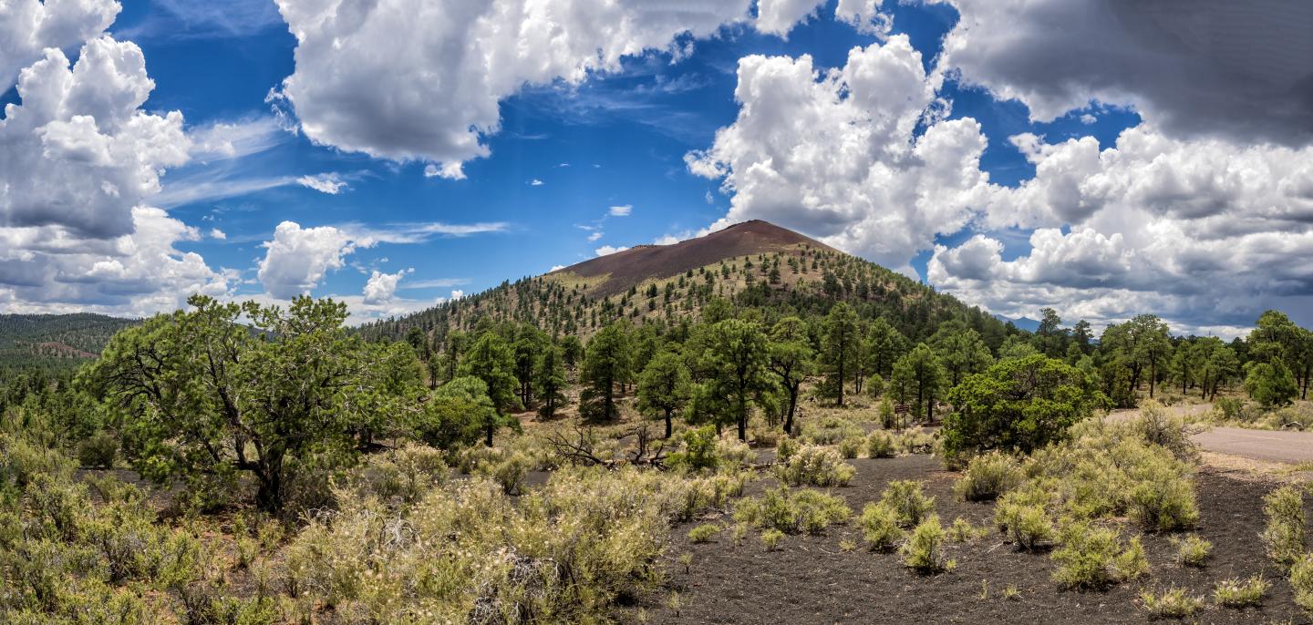 Sunset Crater Volcano under a blue sky and white clouds.