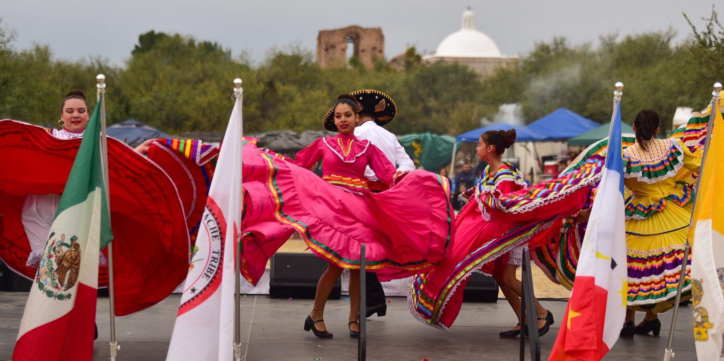 Colorful dancers in traditional dresses performing outdoors.