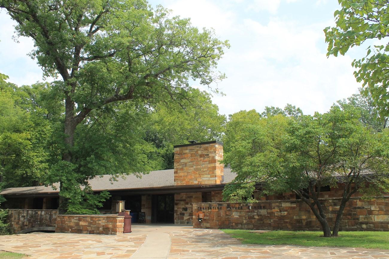 Stone building surrounded by trees under a partly cloudy sky.
