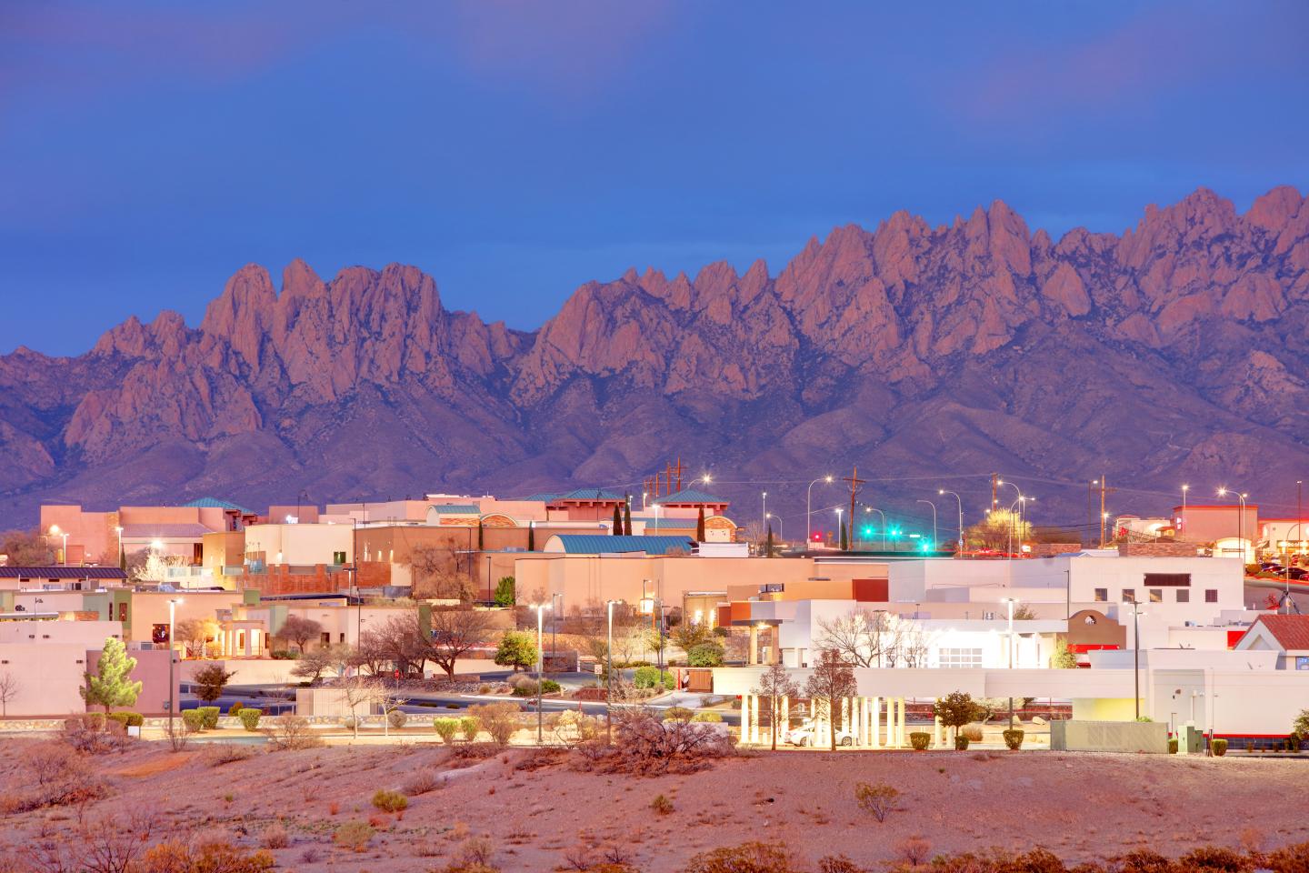 Twilight cityscape with mountains and colorful sky.