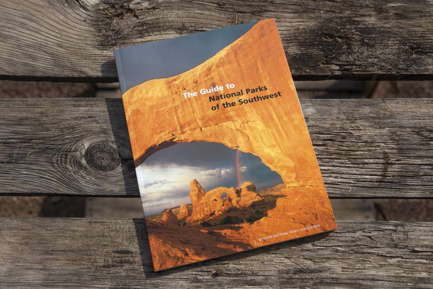 Book with a desert landscape cover on a wooden table.