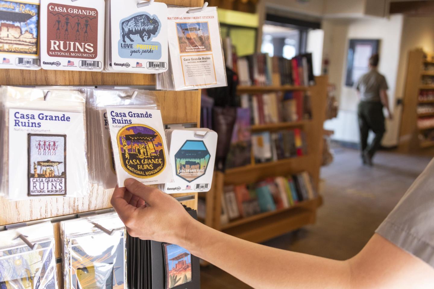 Hand reaching for postcards on a display rack in a bookstore.