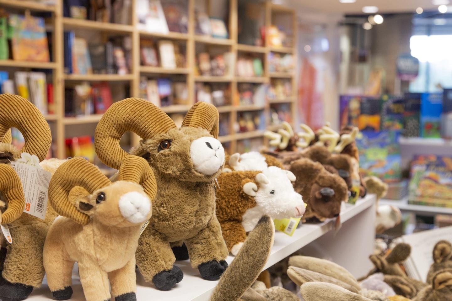 Plush animal toys on a store shelf in front of a book display.