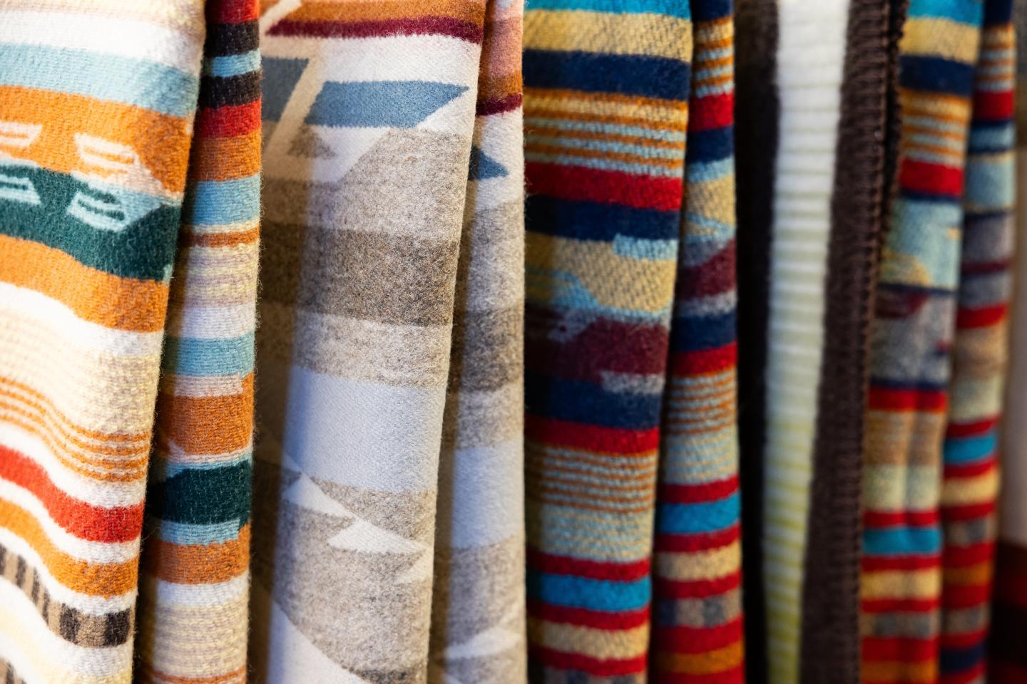 Colorful patterned blankets hanging side by side.