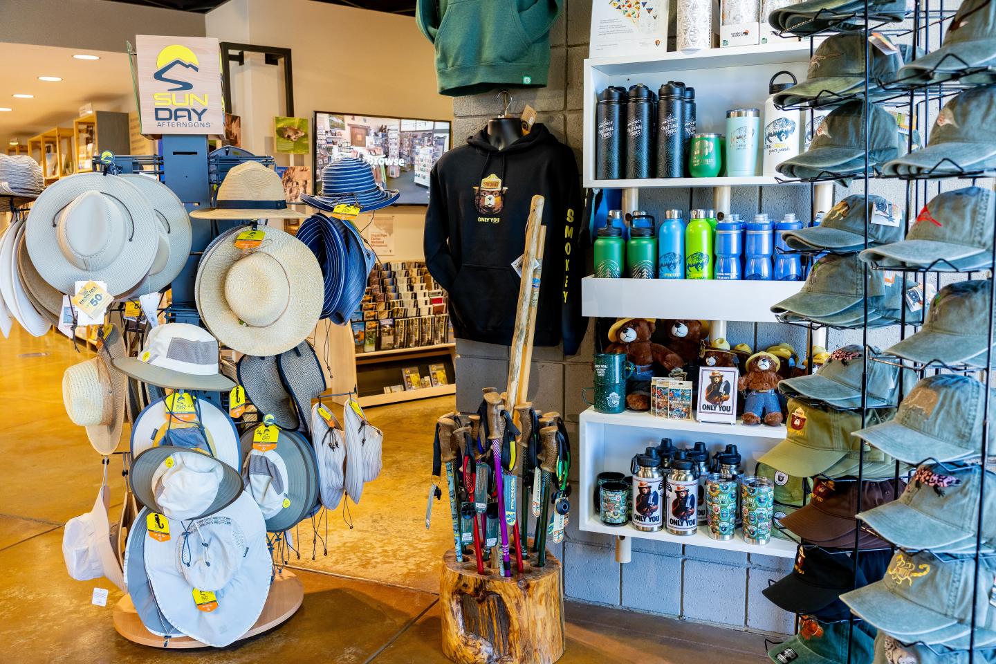 Store interior displaying hats, water bottles, and clothing on shelves.