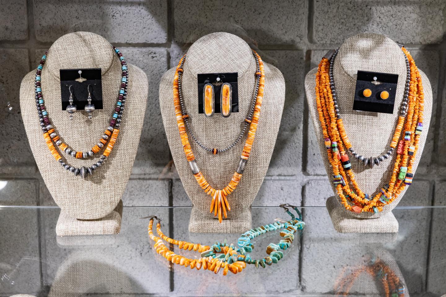 Native American jewelry display with orange bead necklaces and earrings.