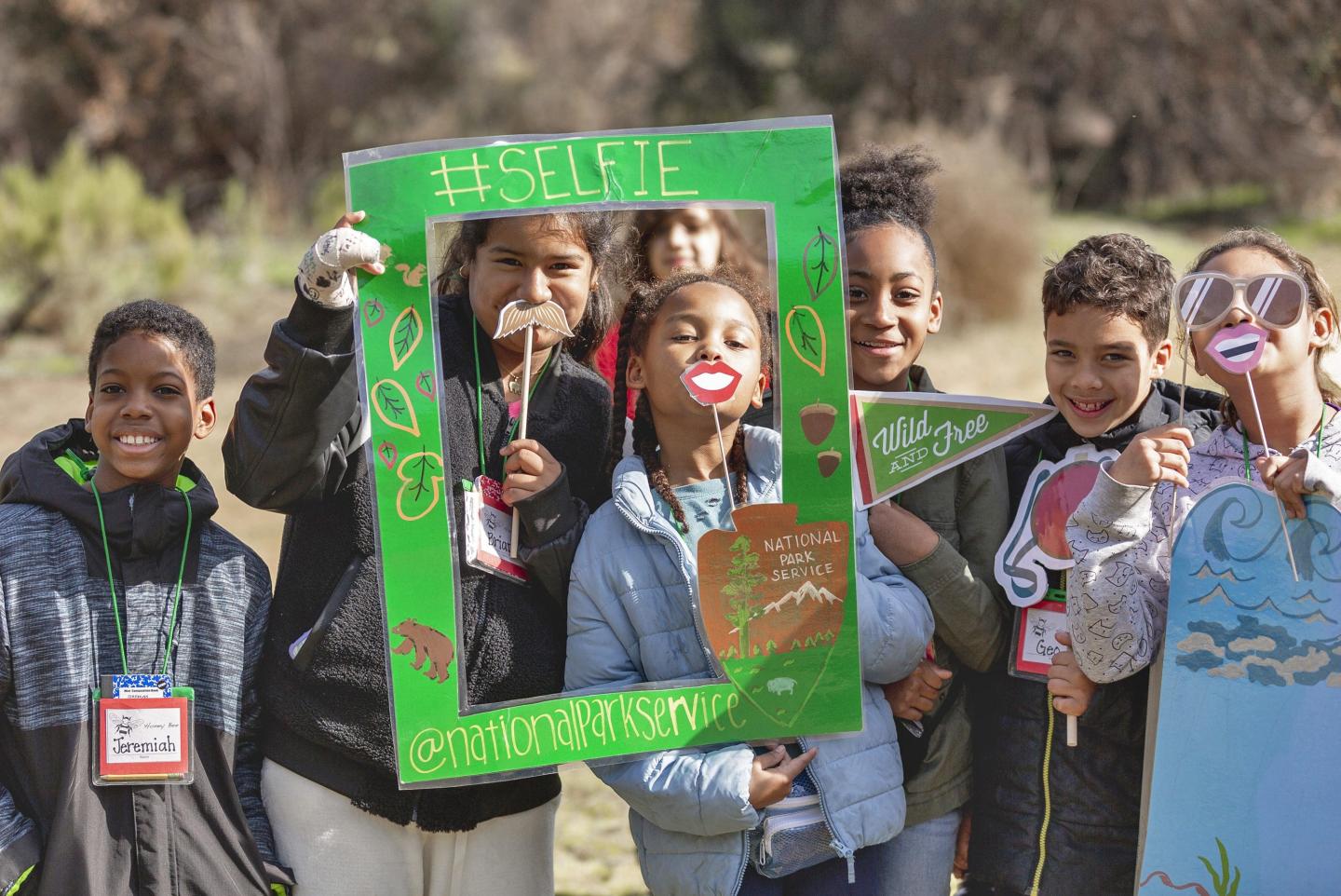 Children smiling with props outdoors, enjoying a playful group photo.