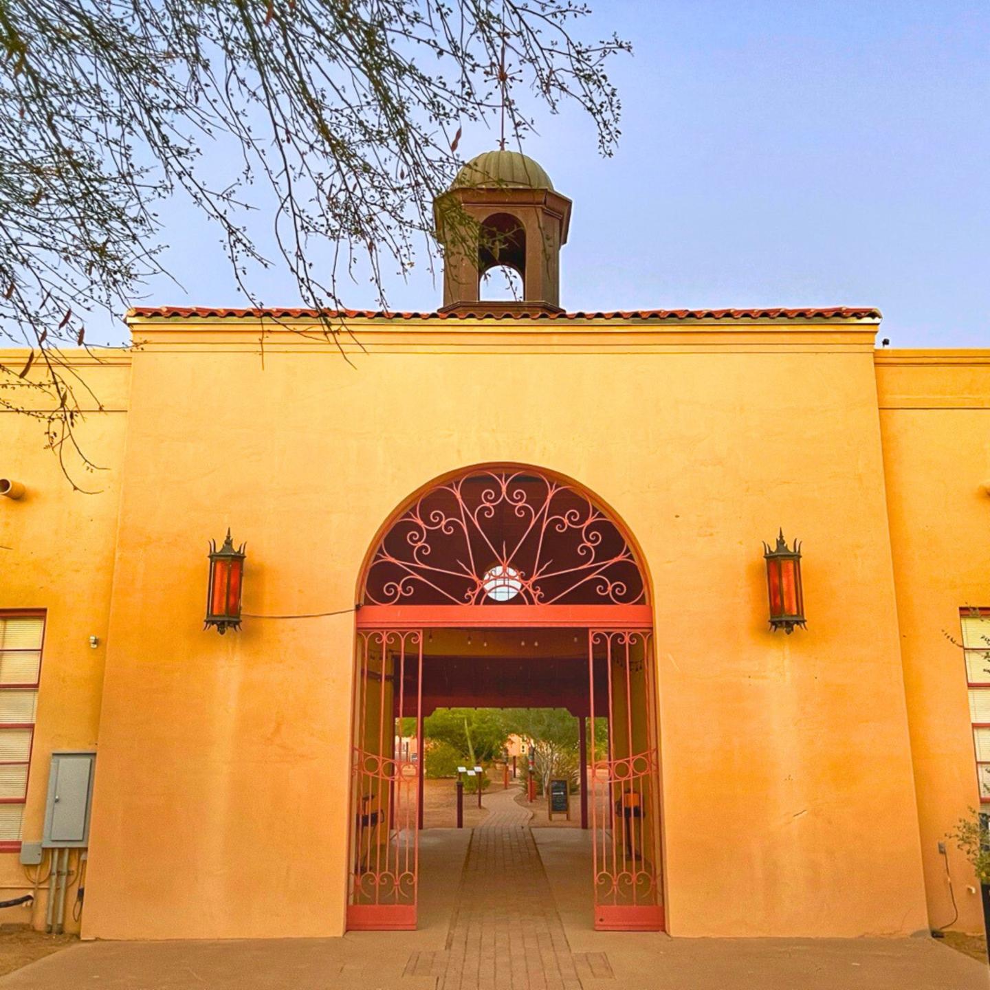 Arched entrance to a yellow building with a small dome on top.
