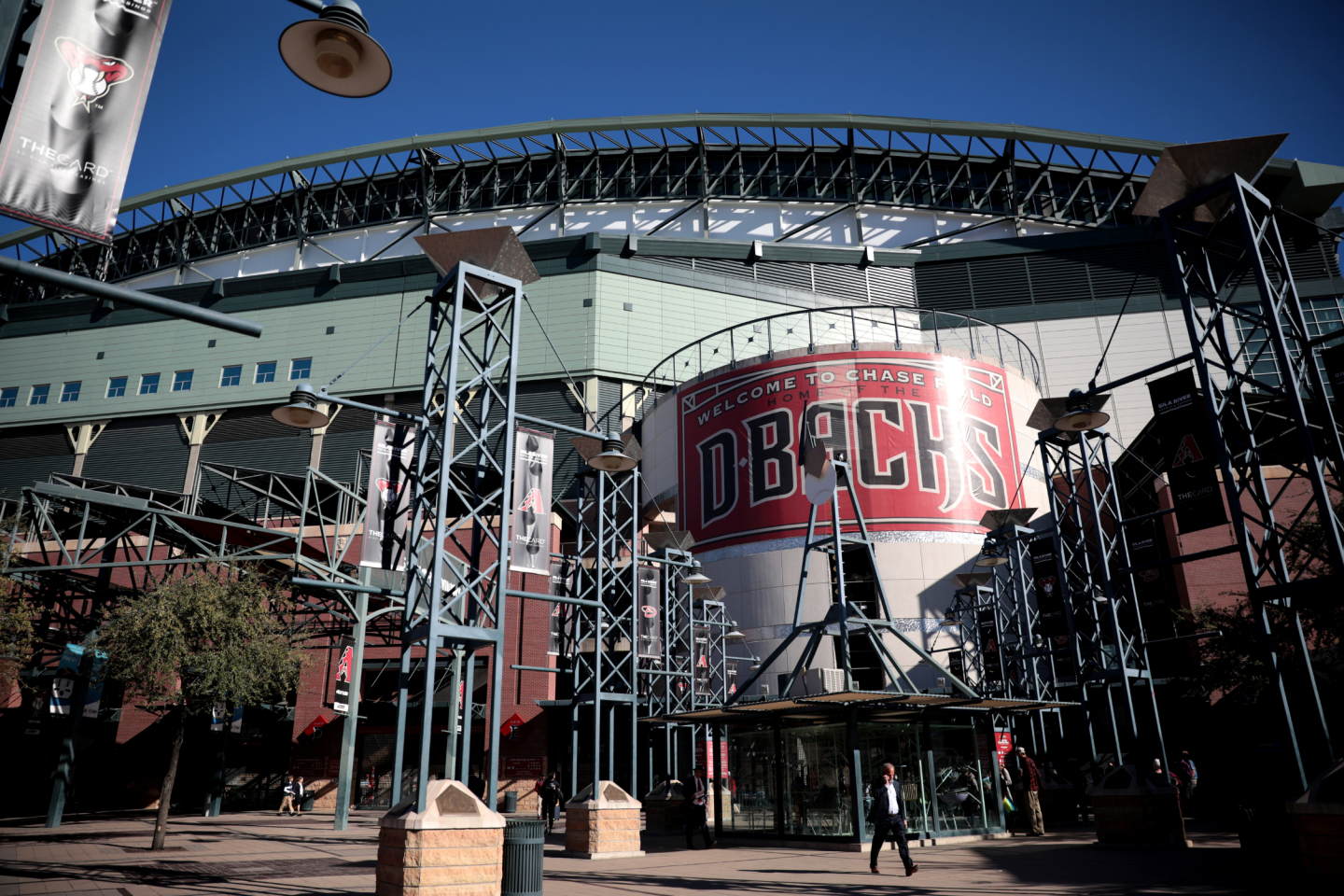 Modern stadium entrance with metal structures under clear blue sky.