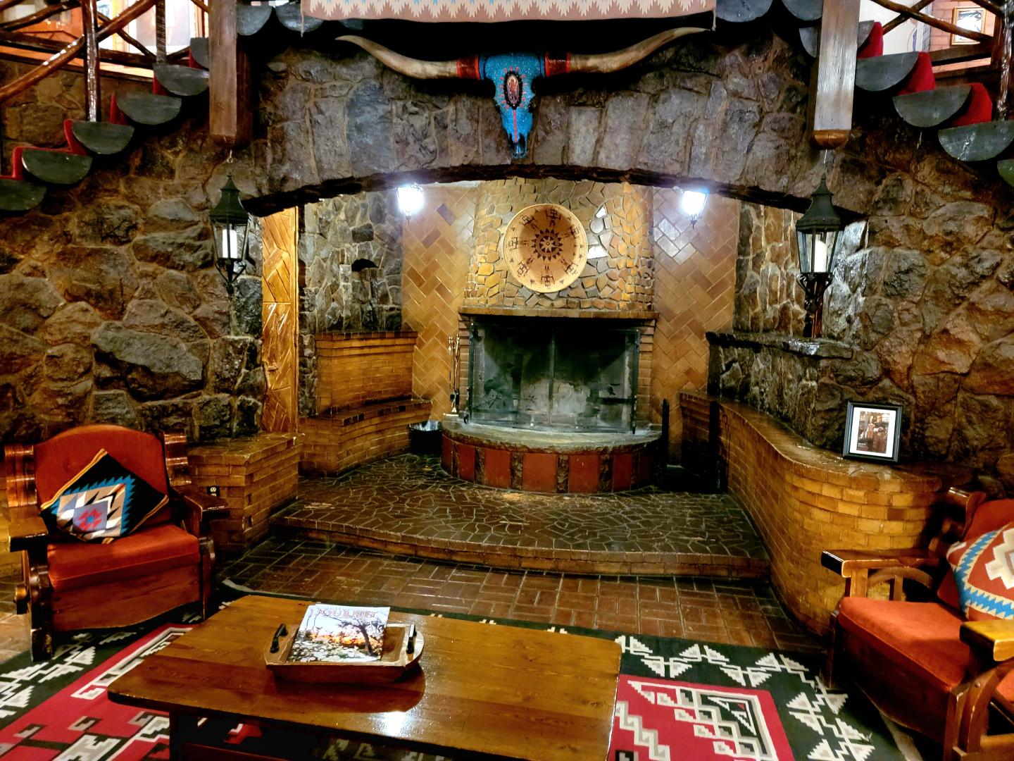 Rustic stone fireplace with wooden accents in cozy living room setting.