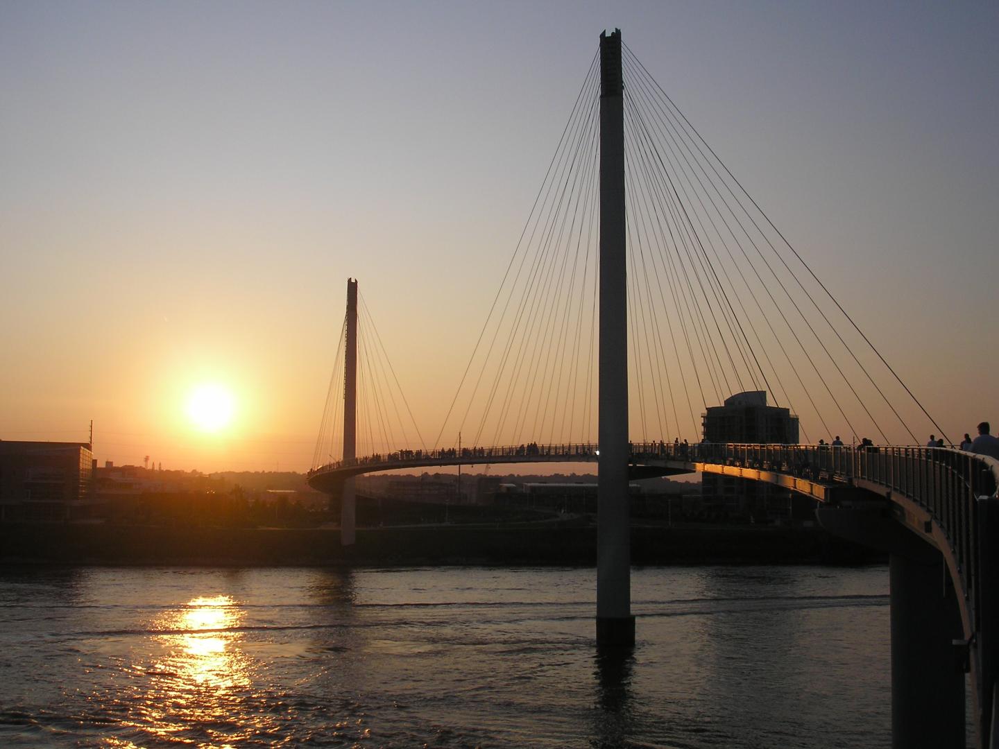 Cable-stayed bridge at sunset over calm water.