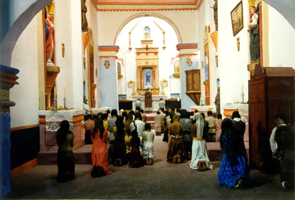 People kneeling inside a church, facing the altar.