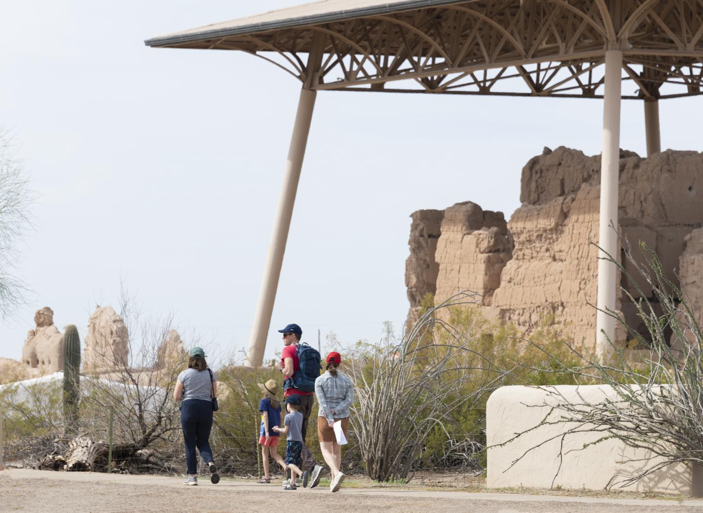 People walking near ancient ruins under a large canopy structure.