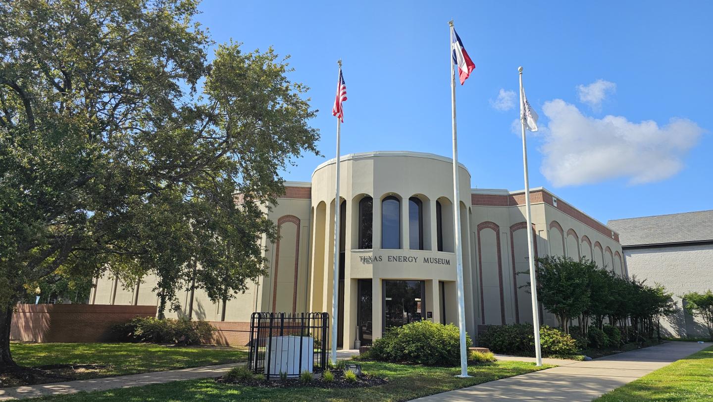 Library building with flags and trees under a blue sky.