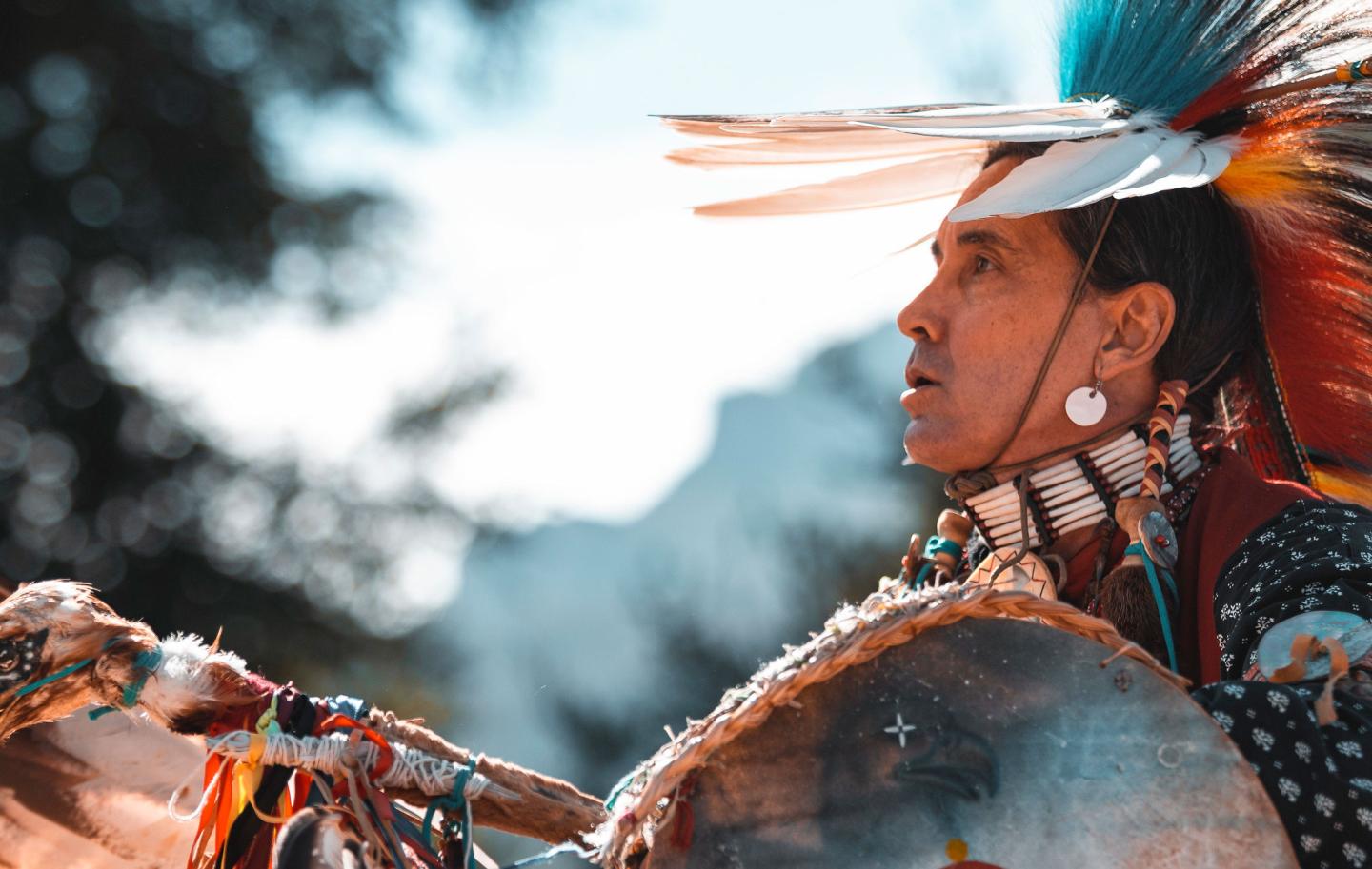 Person in colorful traditional attire with a headdress, outdoors.