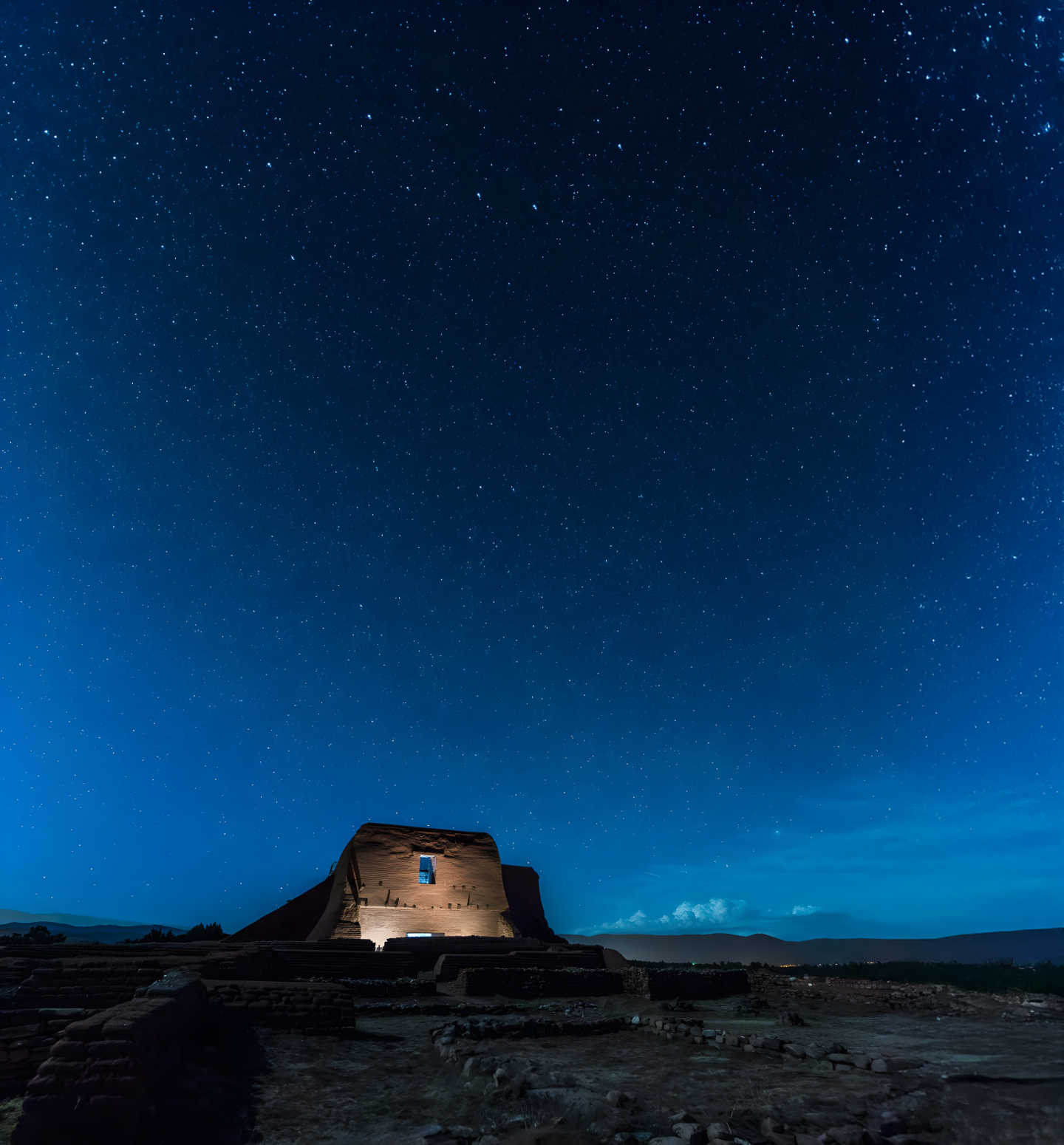 Ruins under a starry night sky with a faint blue glow.