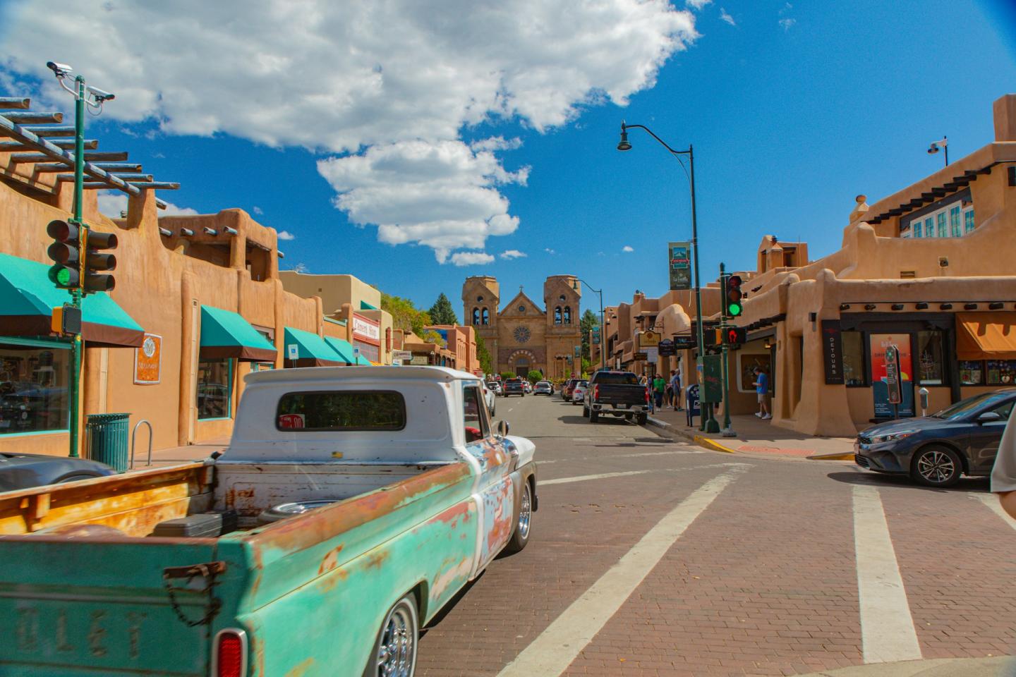 Vintage truck on a sunny street with adobe buildings and clear blue sky.
